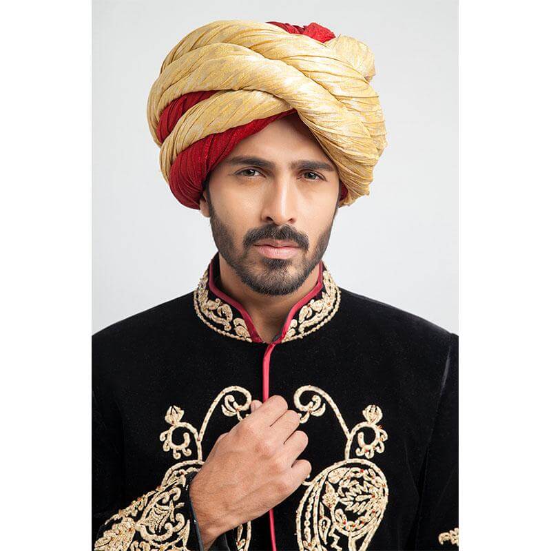 Close-up headshot of an Arsalan Iqbal black velvet sherwani featuring an embroidered gold mandarin collar and a layered gold and red silk turban.