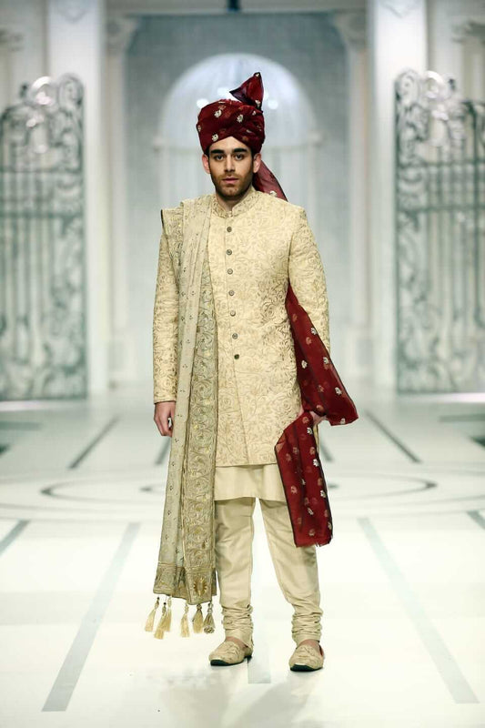 Medium portrait of a man wearing a black Arsalan Iqbal sherwani featuring gold embroidery on the cuffs and a maroon brocade turban.