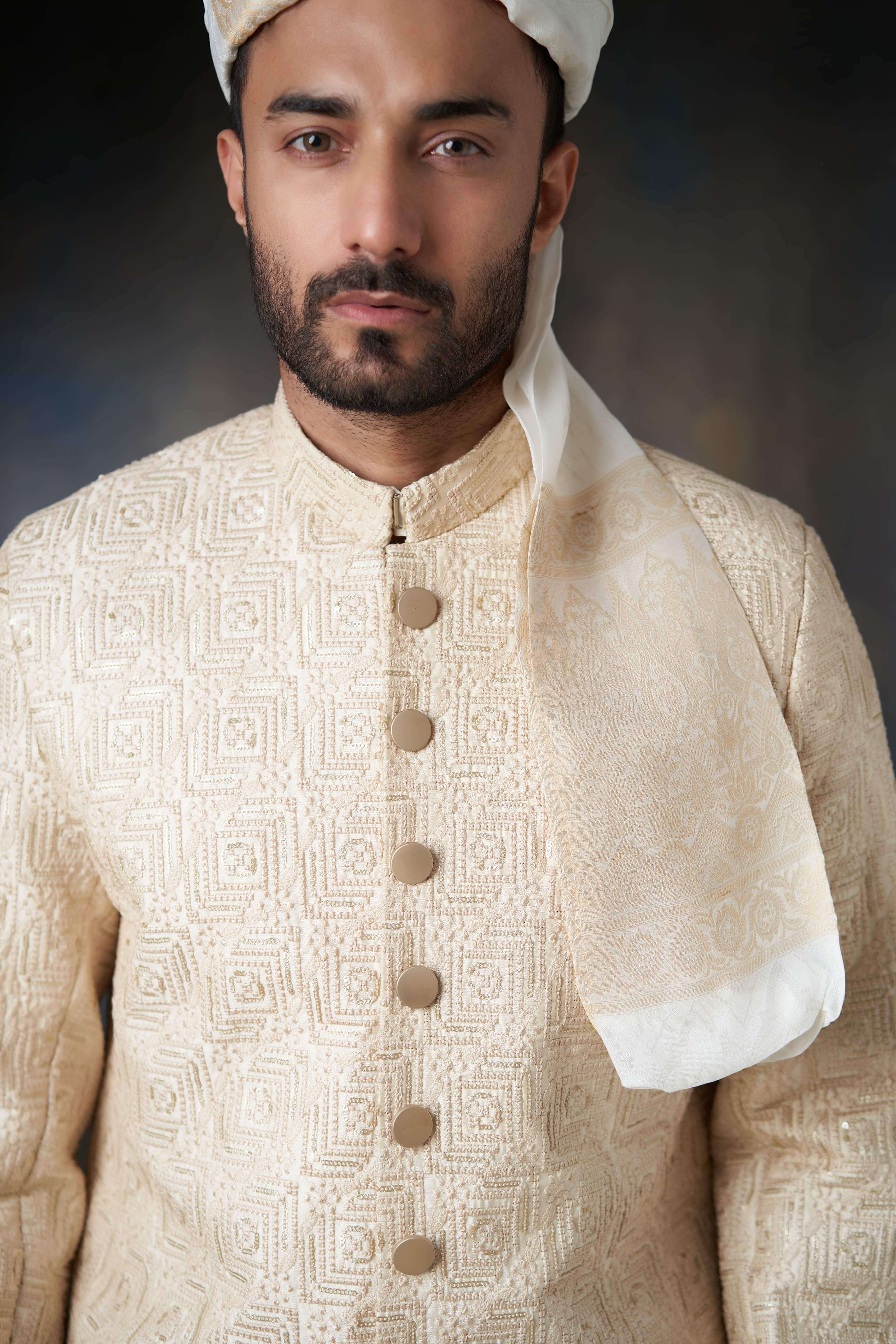 Arsalan Iqbal ivory sherwani featuring complex square-grid and swirl embroidery, gold-toned buttons, and a matching silk turban drape.