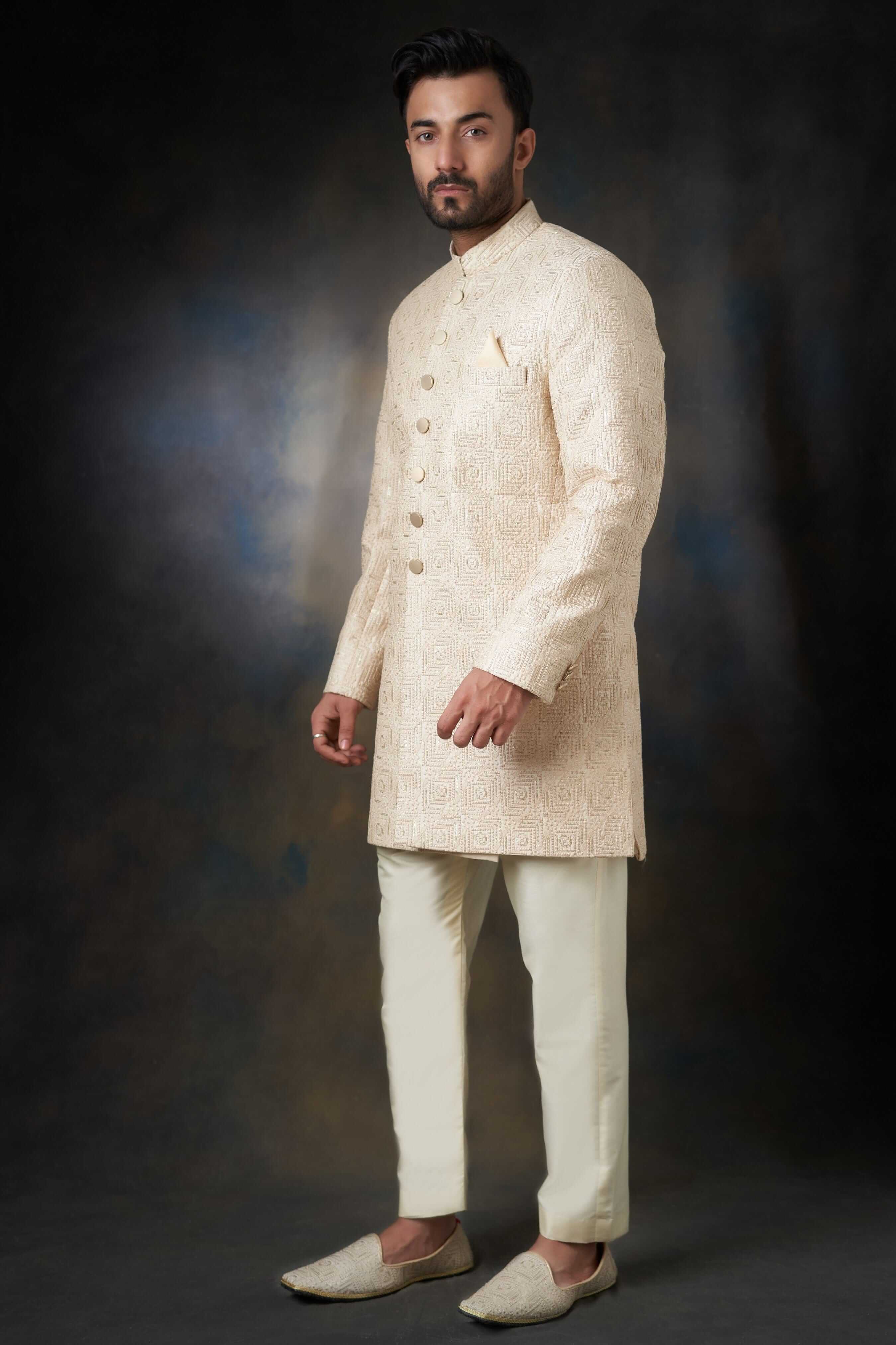 Arsalan Iqbal ivory silk sherwani featuring self-on-self swirl embroidery, gold buttons, and a matching pocket square, paired with cream trousers and embroidered khussas.