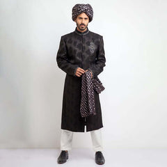 Side profile portrait of a man in an Arsalan Iqbal charcoal grey jacquard sherwani featuring silver chest embroidery and a draped silver polka dot silk shawl.