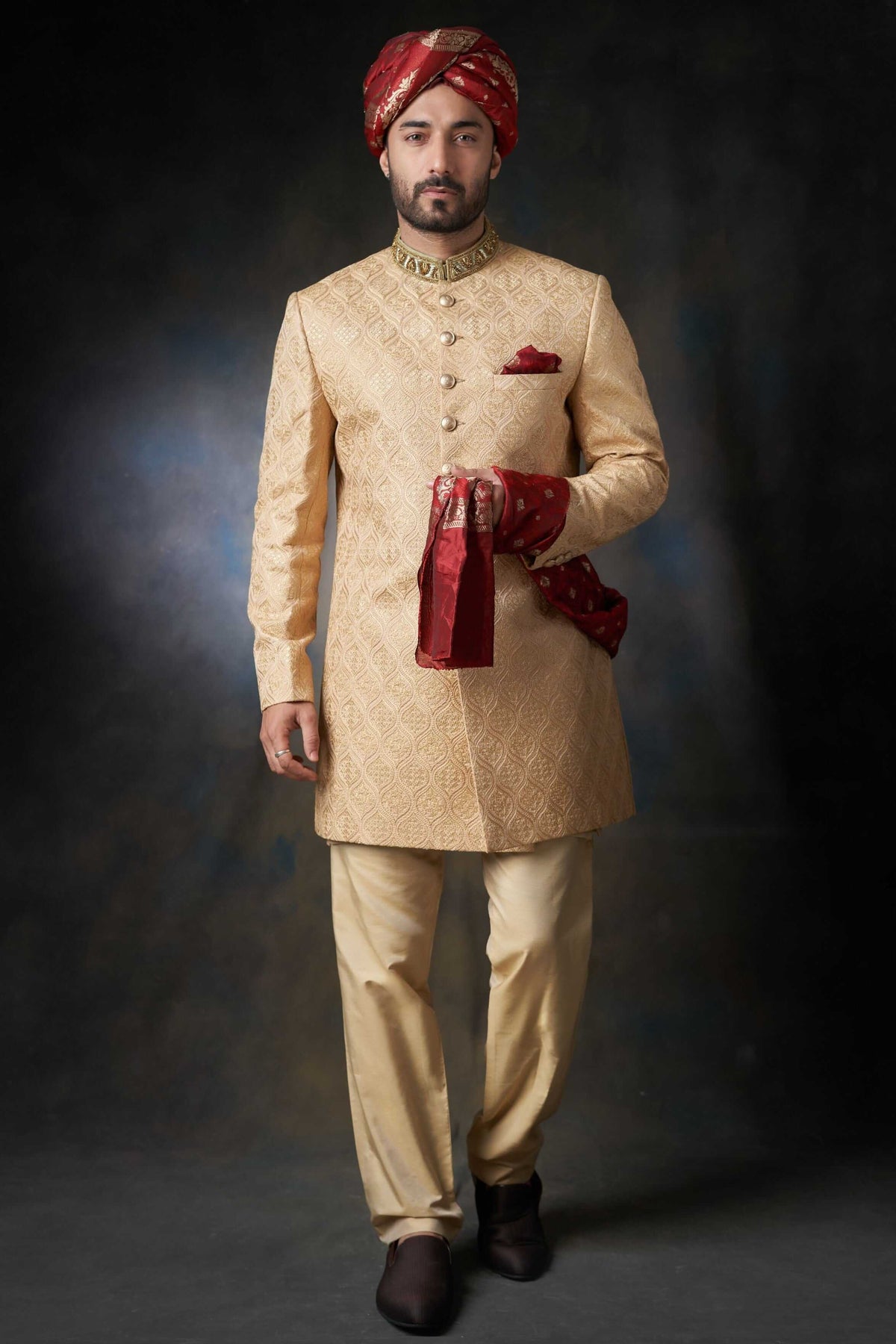Arsalan Iqbal gold silk sherwani with damask embroidery, featuring a ruby-red velvet turban, matching pocket square, and shawl, paired with cream trousers.
